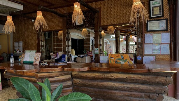 A wooden reception desk with a woven ceiling and hanging light fixtures.