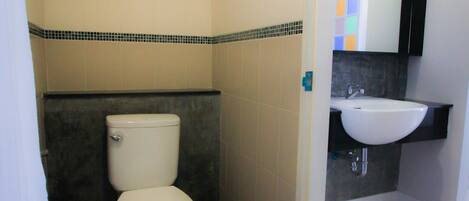 A bathroom with a toilet, sink, and tiled walls.