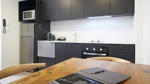 A modern kitchen with dark cabinets, a microwave, a coffee maker, and a dining table with chairs. - Kelly Rd Cambridge Lodge (Cambridge)