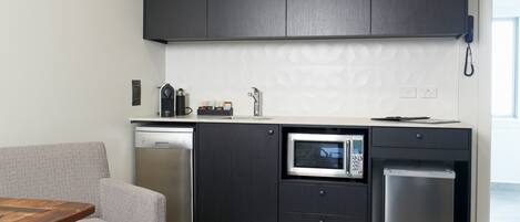 Une cuisine moderne avec des meubles de rangement sombres, un four à micro-ondes encastré et un lave-vaisselle.