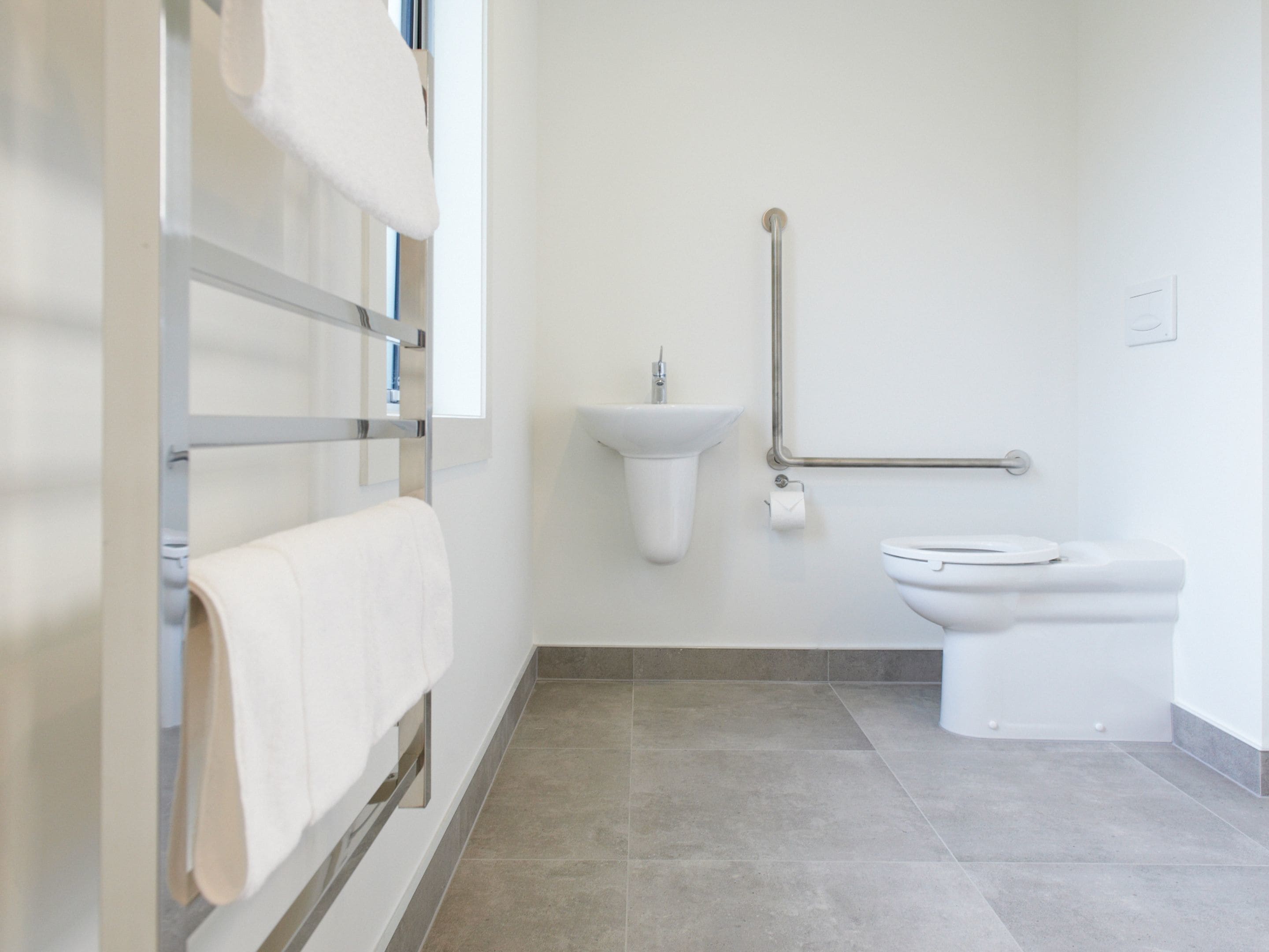 A bathroom with a toilet, sink, and towel rack.