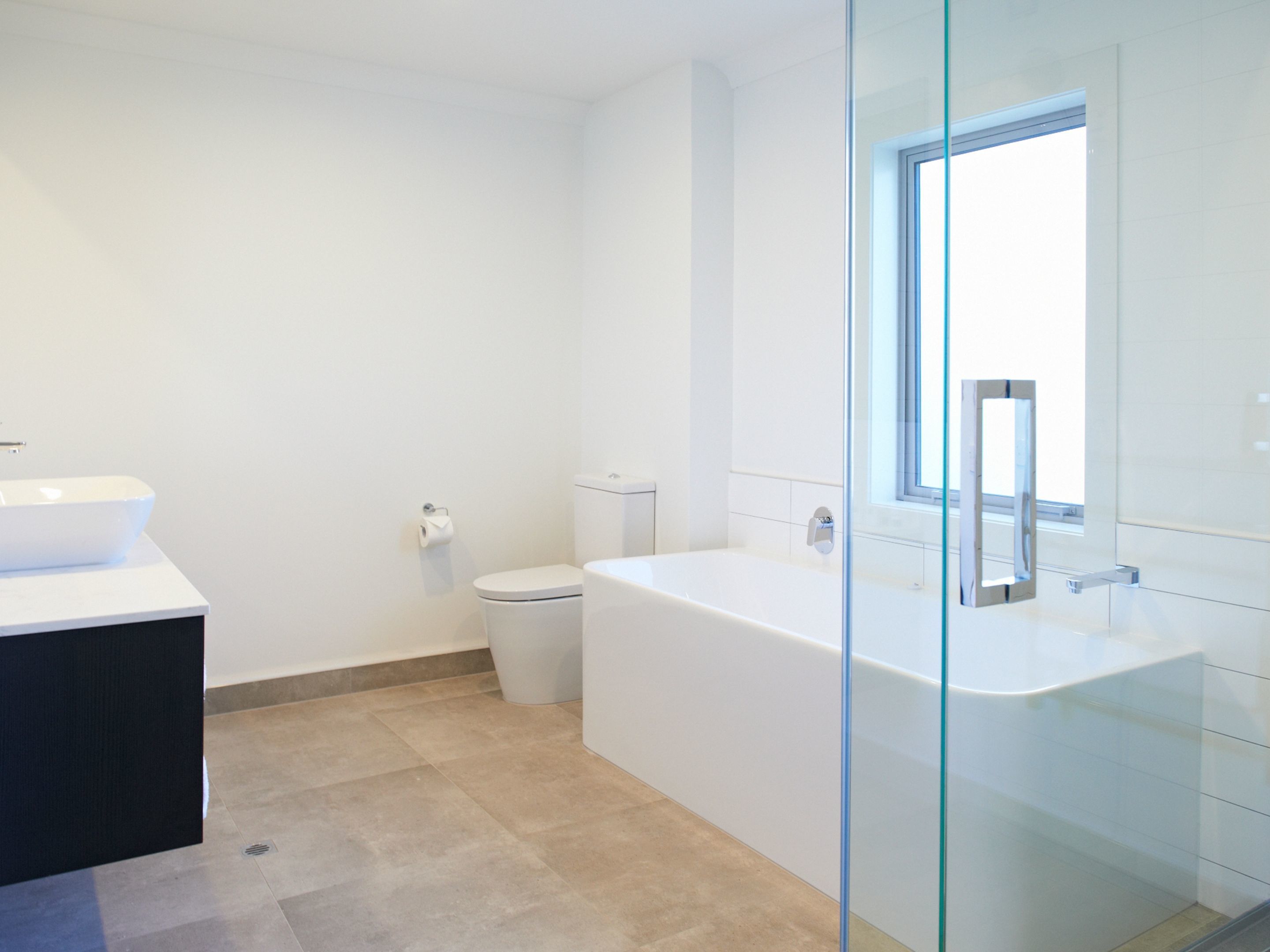 A modern bathroom with a glass-enclosed shower, a white toilet, and a large bathtub.