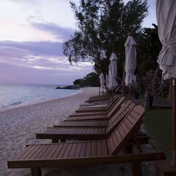 Na praia, areia branca, espreguiçadeiras, guarda-sóis