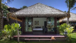 A thatched-roof structure with a bed, seating area, and a small table. - Mali Resort Sunrise Beach (Koh Lipe)