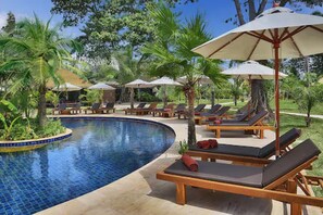 Una piscina al aire libre, sombrillas, tumbonas