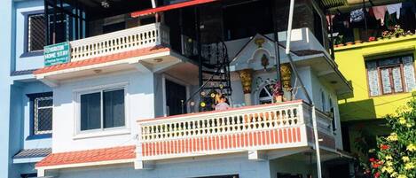 A multi-story building with balconies, a visible sign for Horizon Home Stay, and a red-tiled roof.