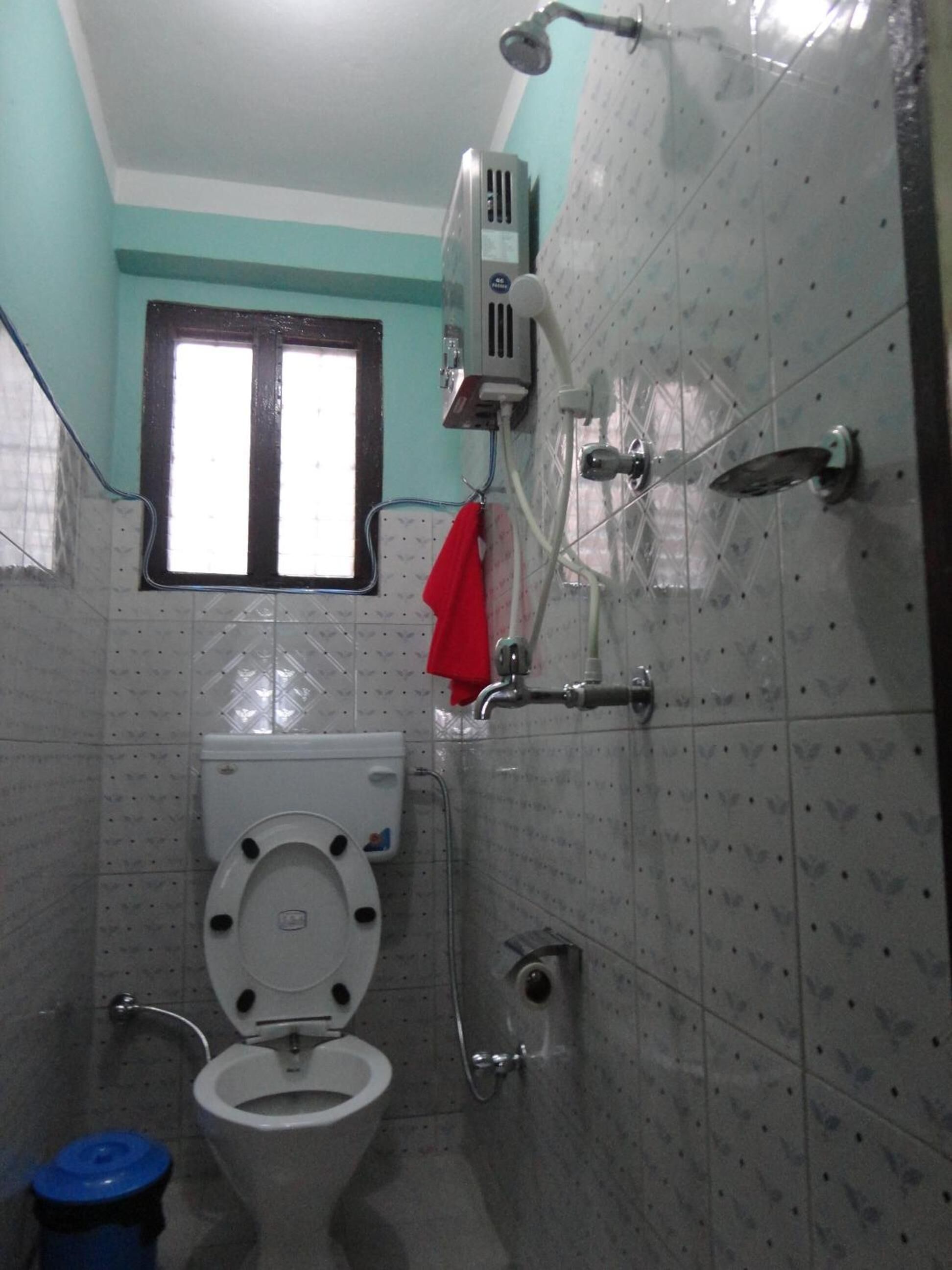 Une salle de bain avec des toilettes, une douche et une fenêtre.