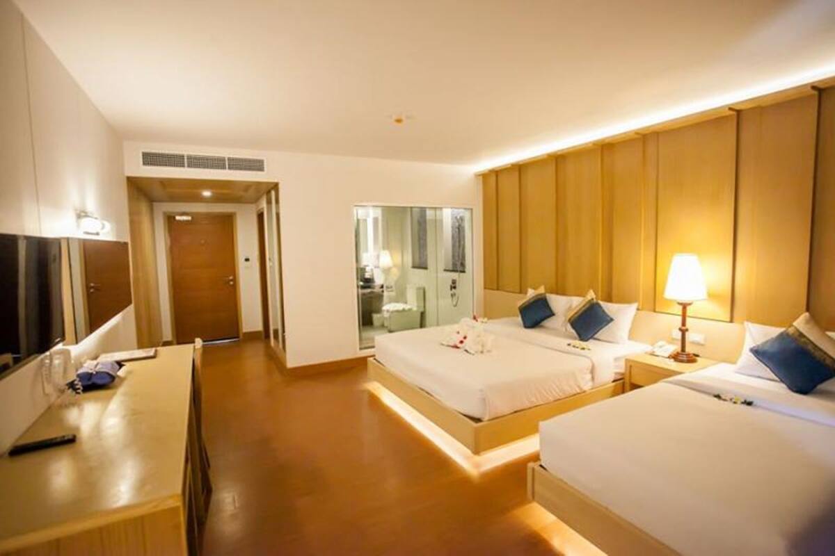 A hotel room with a large bed, a desk, and a TV. There is a mirror and a door leading to a bathroom.