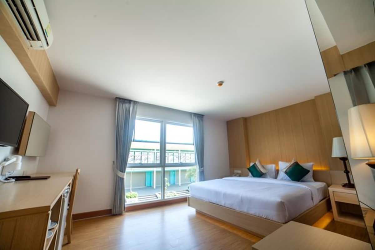 A modern hotel room with a large bed, a desk, and a TV.