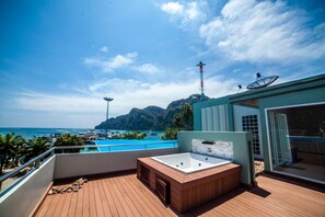 A wooden deck with a hot tub and a glass-enclosed area, overlooking a clear blue sea and mountains. - Phi Phi Harbour View Hotel (Ko Phi Phi)