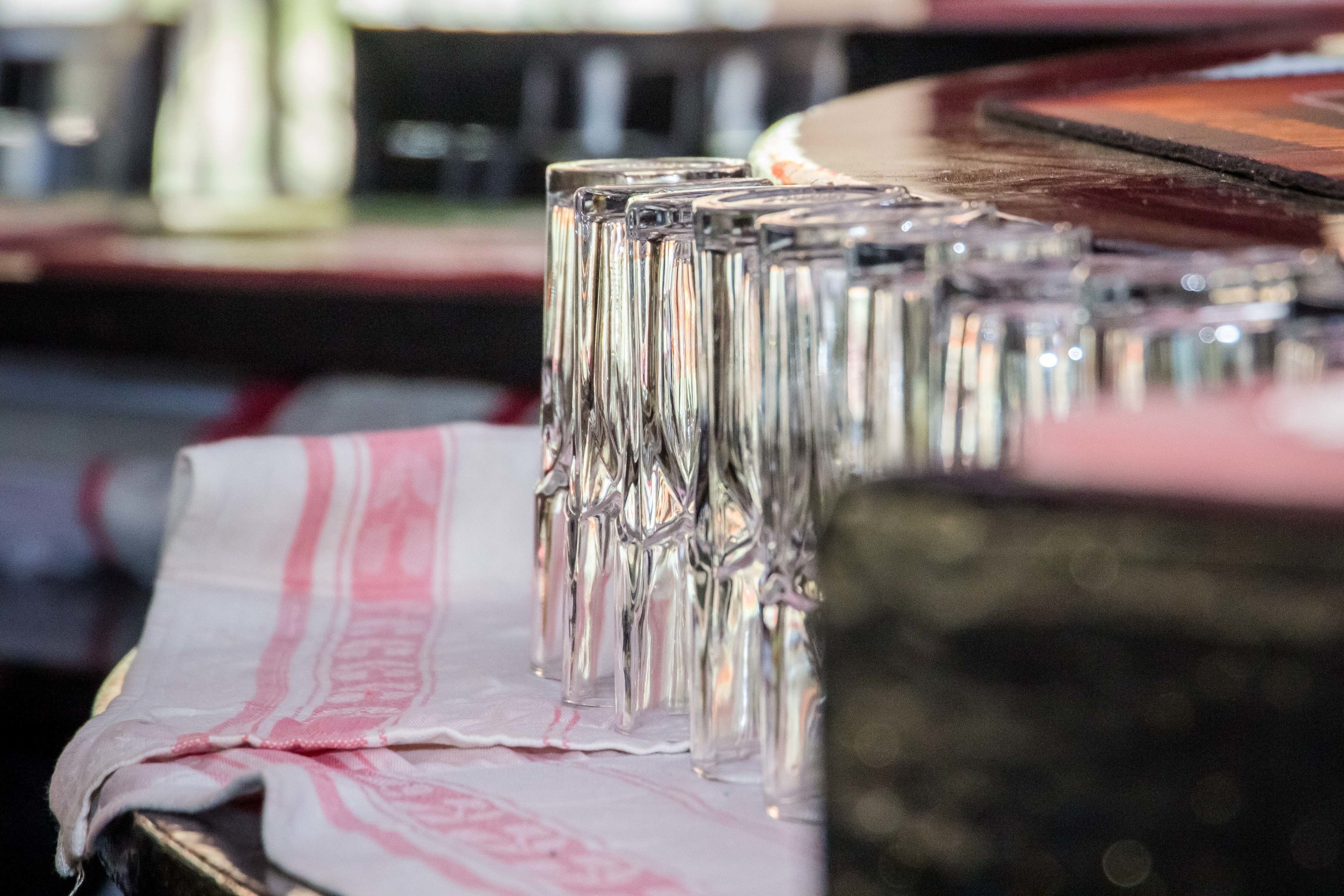 A row of clear glasses on a table with a patterned cloth.