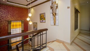 Una escalera con barandilla de madera y pasamanos de metal, que lleva a una habitación con un papel tapiz estampado y un cuadro de flores.