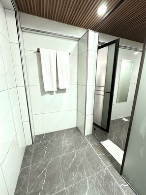 Een moderne badkamer met een douchecabine van glas, een marmeren vloer en een grote spiegel.