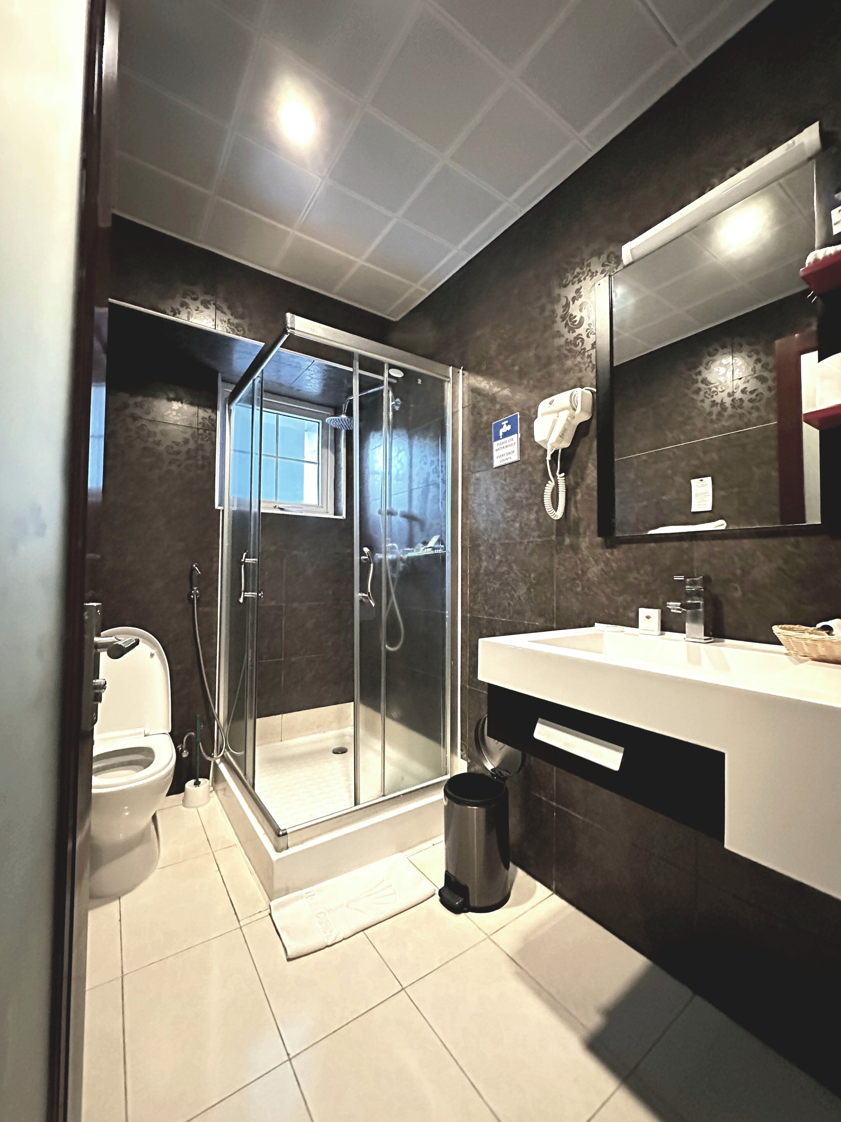A modern bathroom with a glass-enclosed shower, a toilet, and a vanity with a mirror.