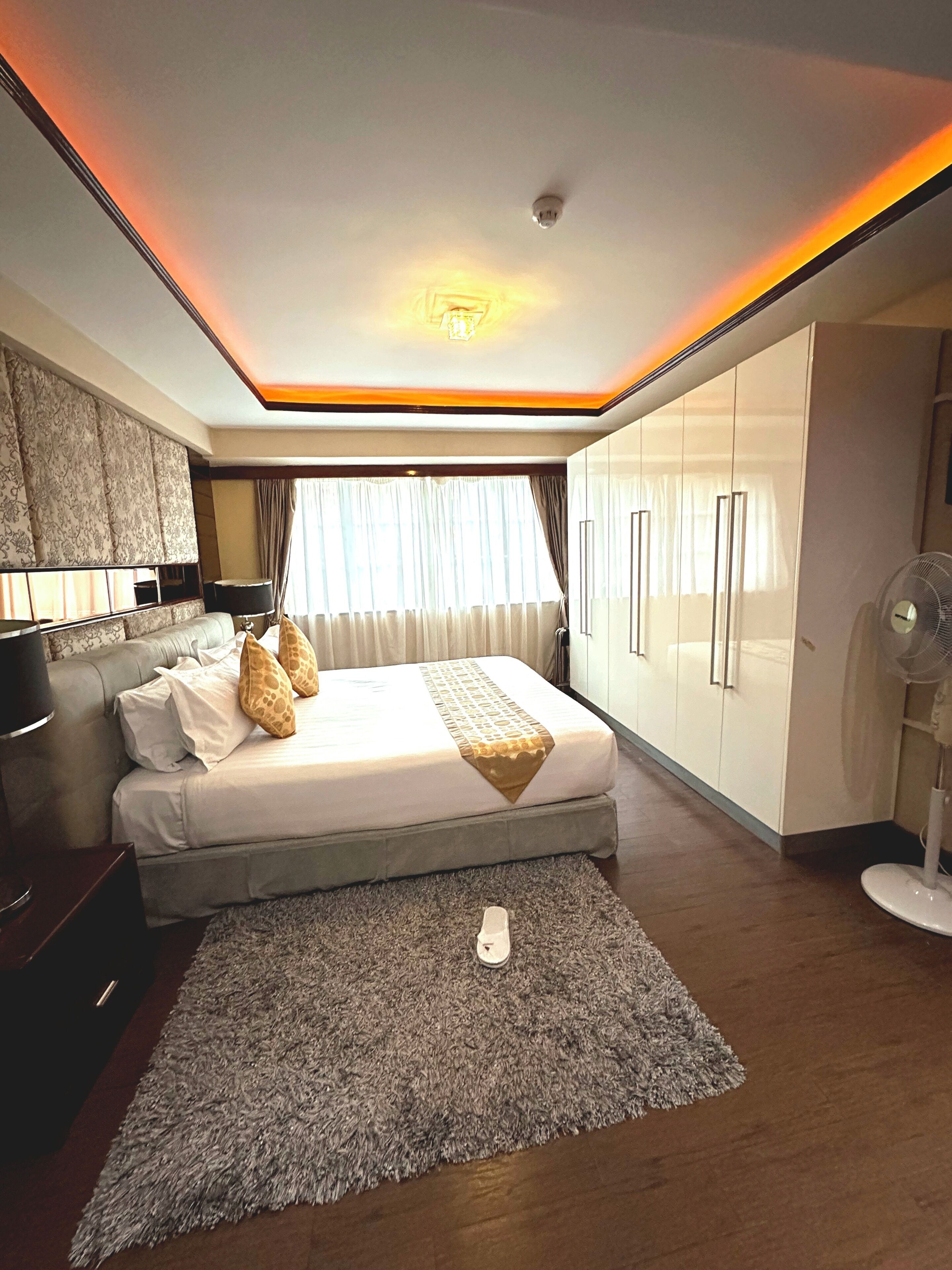 Een moderne slaapkamer met een groot bed, een ventilator en een kledingkast.