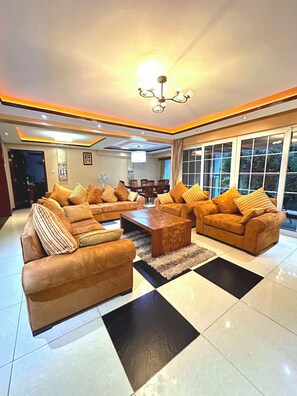 A spacious living room with a large sofa set, a coffee table, and a chandelier. - Clarence House Nairobi (Nairobi)