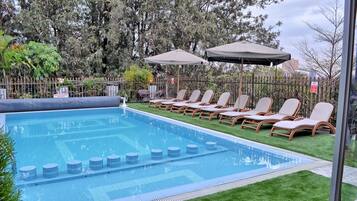 Alberca al aire libre, sombrillas en la alberca y camastros