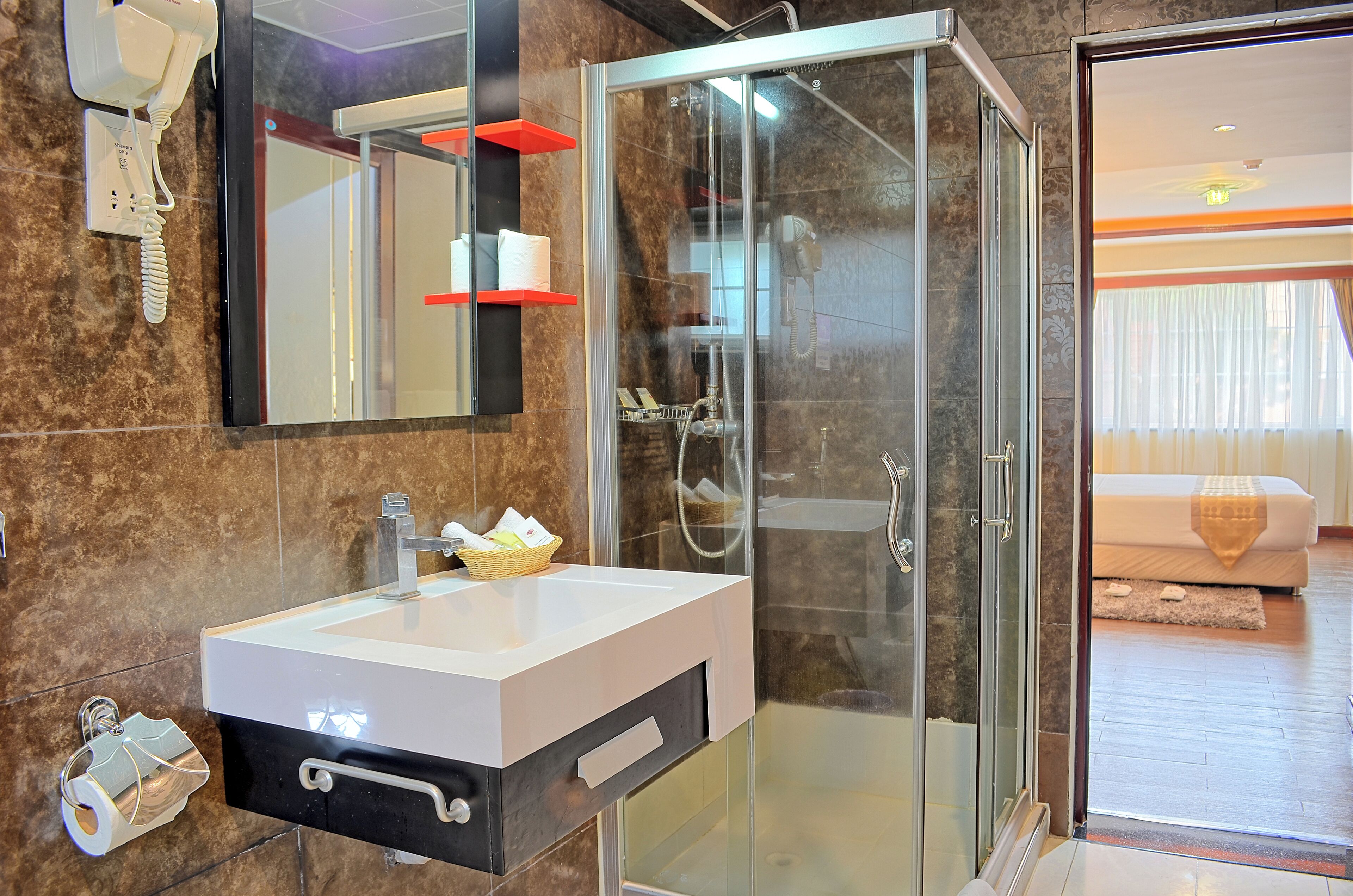 Een moderne badkamer met een glazen douchecabine, een wit wastafelmeubel met een zwarte kast en een spiegel boven de wastafel.