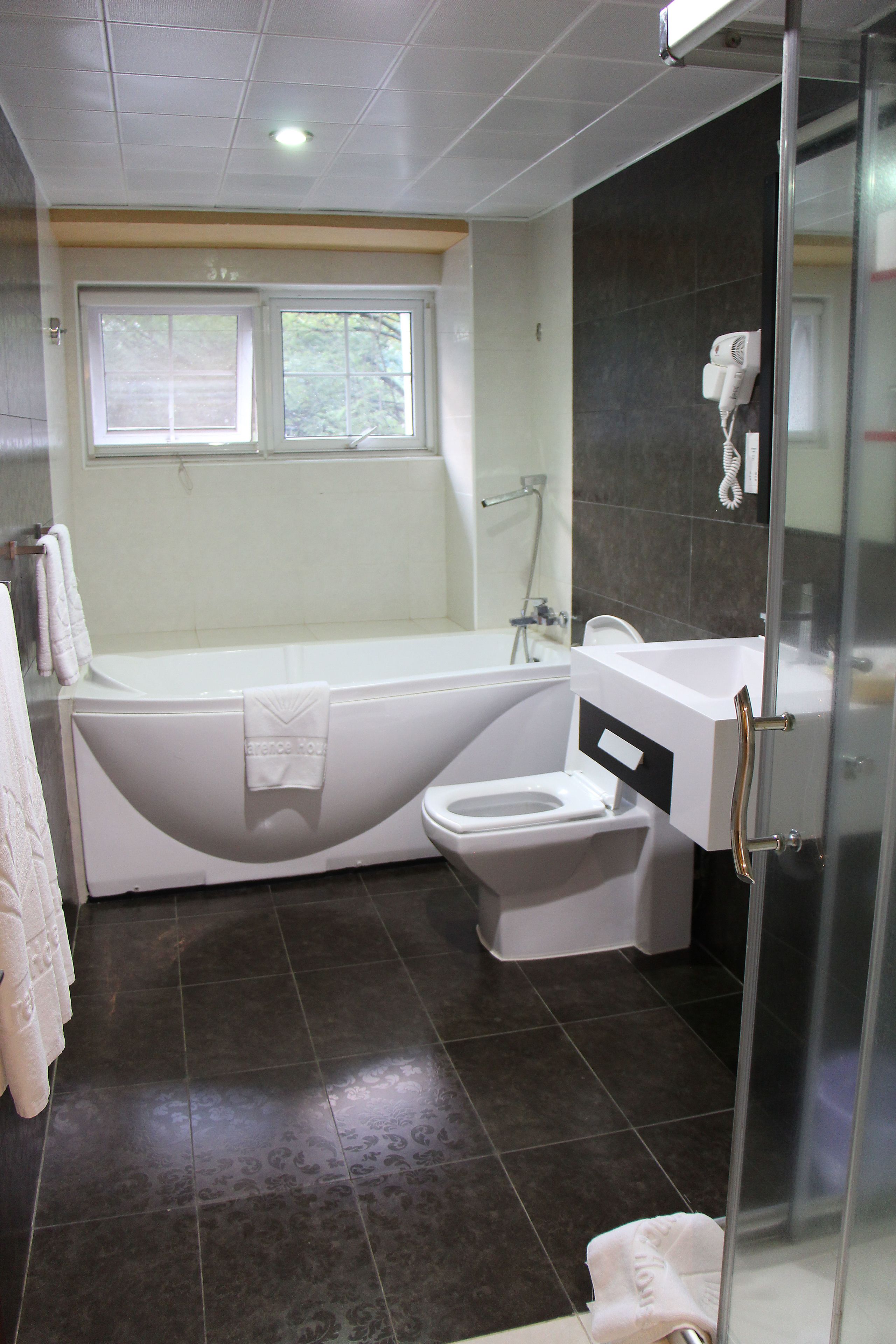 A modern bathroom with a bathtub, toilet, and shower.