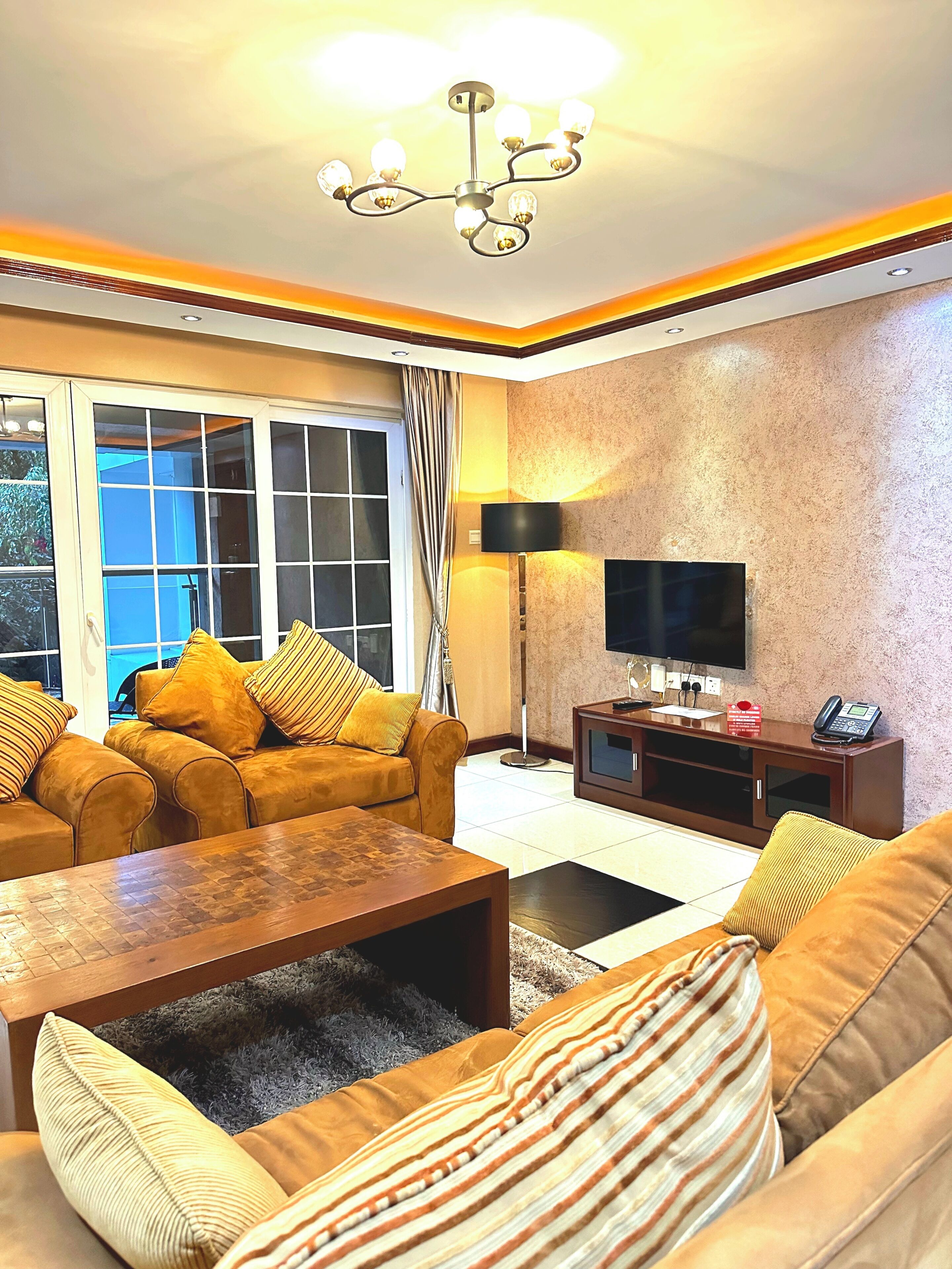 A living room with a sofa set, a coffee table, a TV, and a lamp.