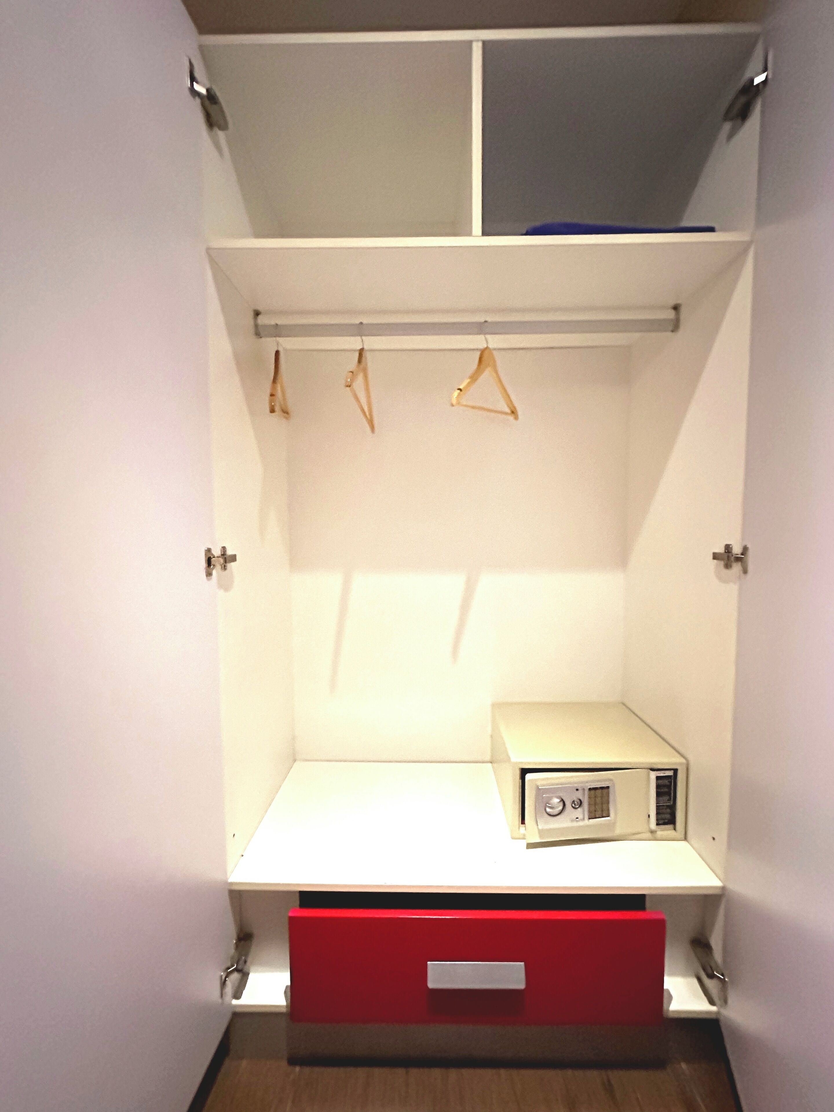 Un vestidor con un estante blanco, un cajón rojo y un pequeño electrodoméstico blanco.