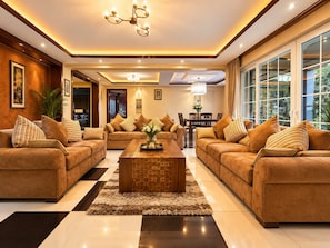 A modern living room with two sofas, a coffee table, and a dining area with a chandelier. - Clarence House Nairobi (Nairobi)