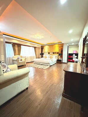 A modern hotel room with a large bed, a sitting area with a sofa, a desk, and a wardrobe. - Clarence House Nairobi (Nairobi)