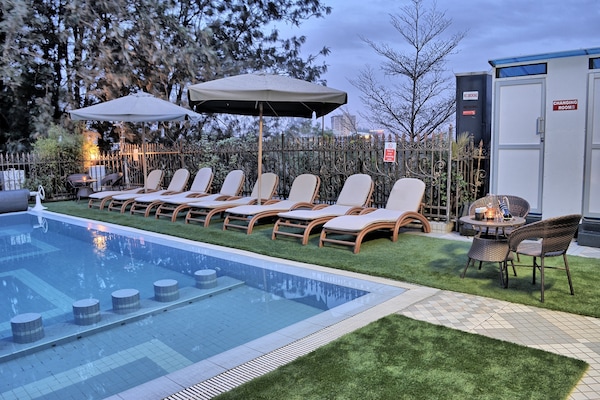 Una piscina al aire libre, sombrillas, tumbonas