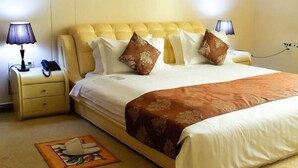 Une chambre d’hôtel avec un grand lit, deux tables de chevet, une lampe et une petite planche à repasser.