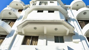 Un edificio de varios pisos con fachada blanca, varios balcones y techo plano.