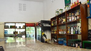 Una zona de bar con estantes llenos de diversas bebidas alcohólicas y un refrigerador.
