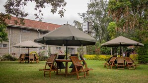 Een terras buiten met een houten tafel en stoelen, omringd door parasols.