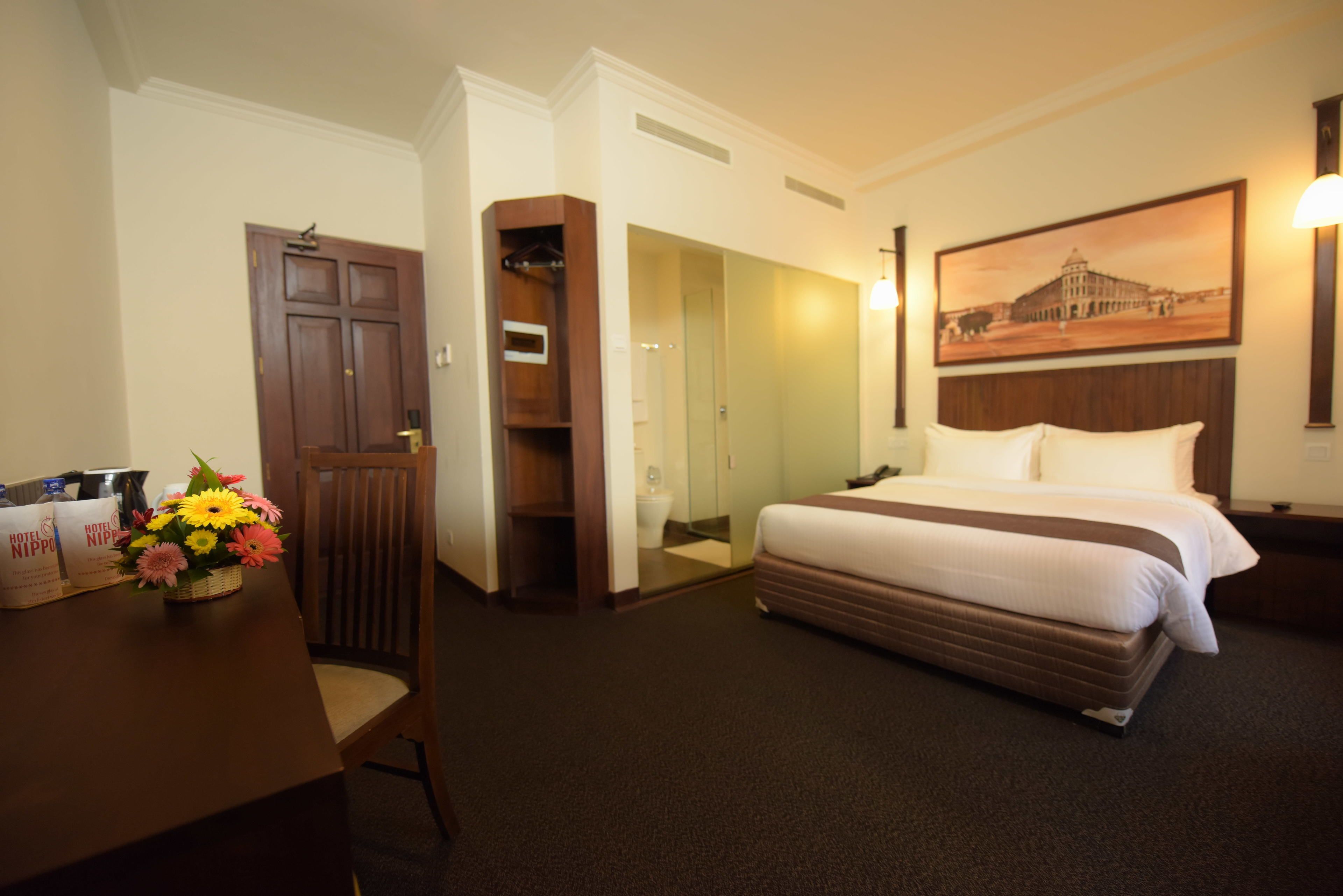 Habitación de hotel con cama, escritorio con silla, baño y zona de comedor con mesa y sillas.