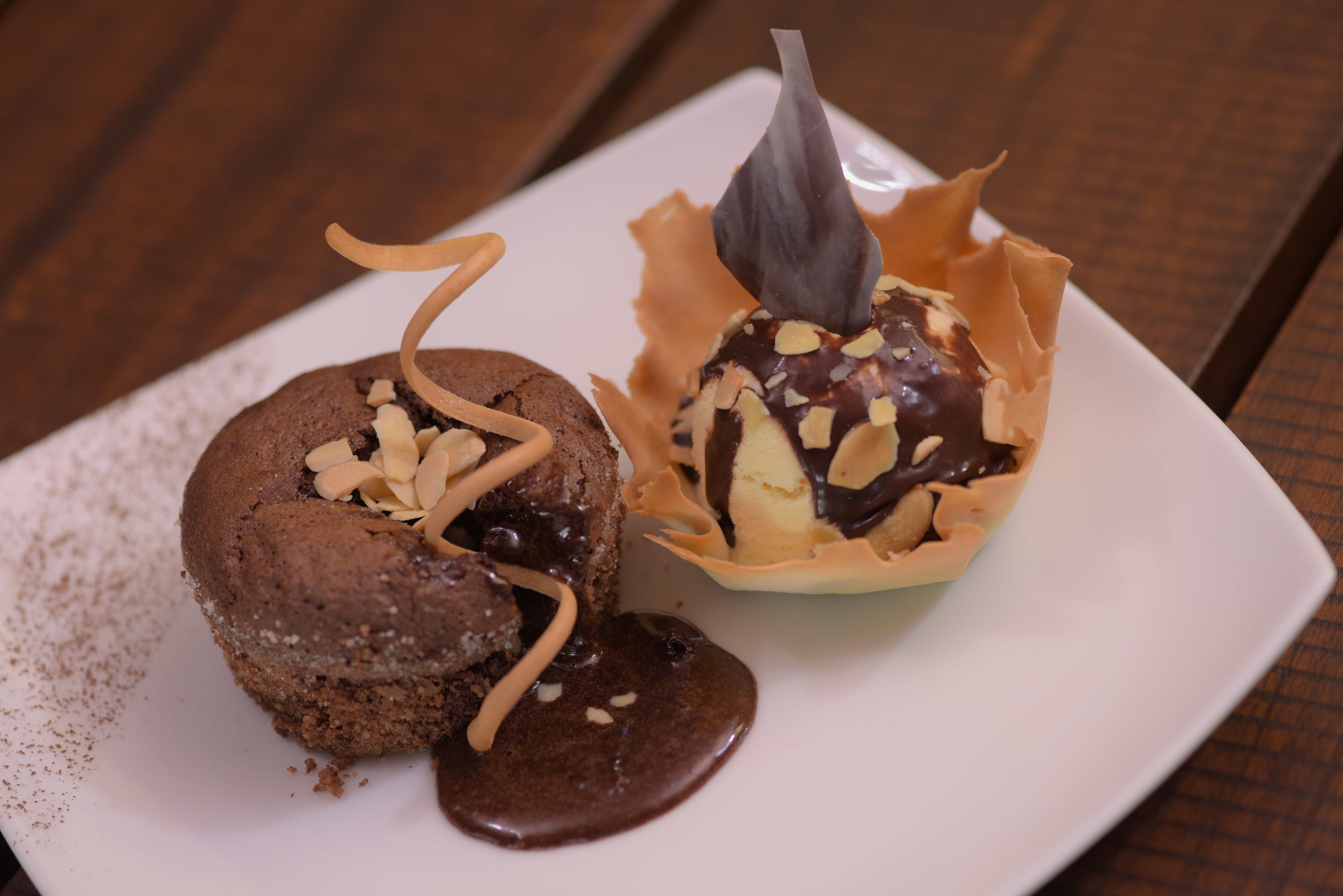 A dessert plate with a chocolate cake and a chocolate-covered ice cream cone.