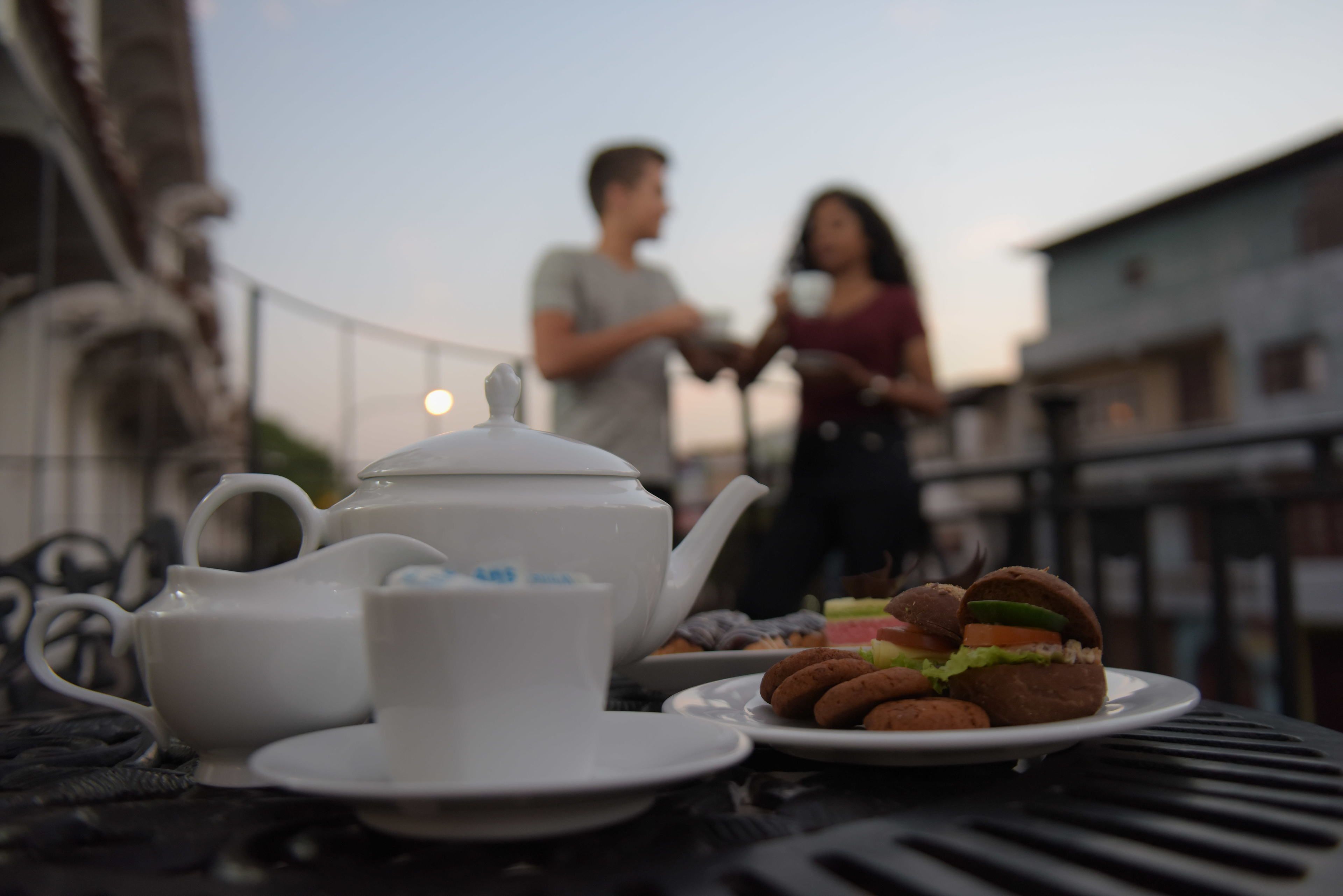 A table with a teapot, cup, plate with cookies, and a sandwich.