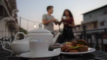 A table with a teapot, cup, plate with cookies, and a sandwich.