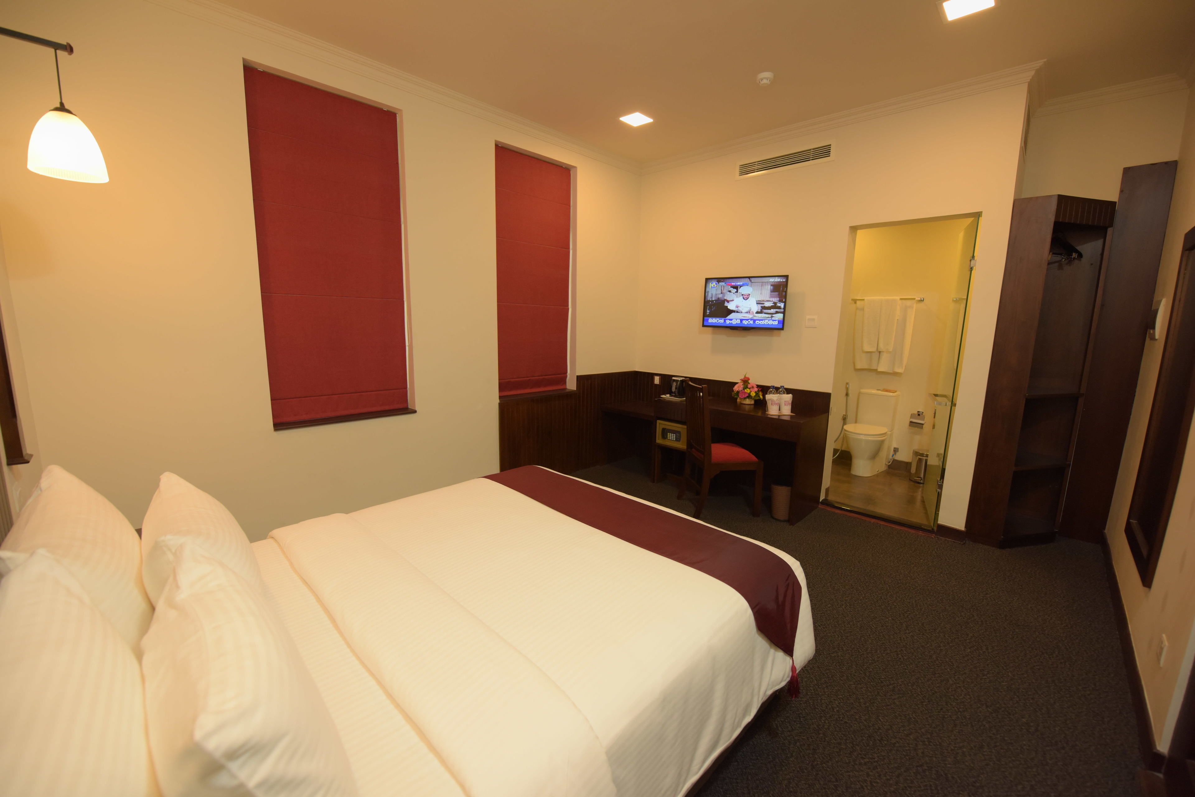 A hotel room with a bed, a desk, a chair, a television, and a bathroom.