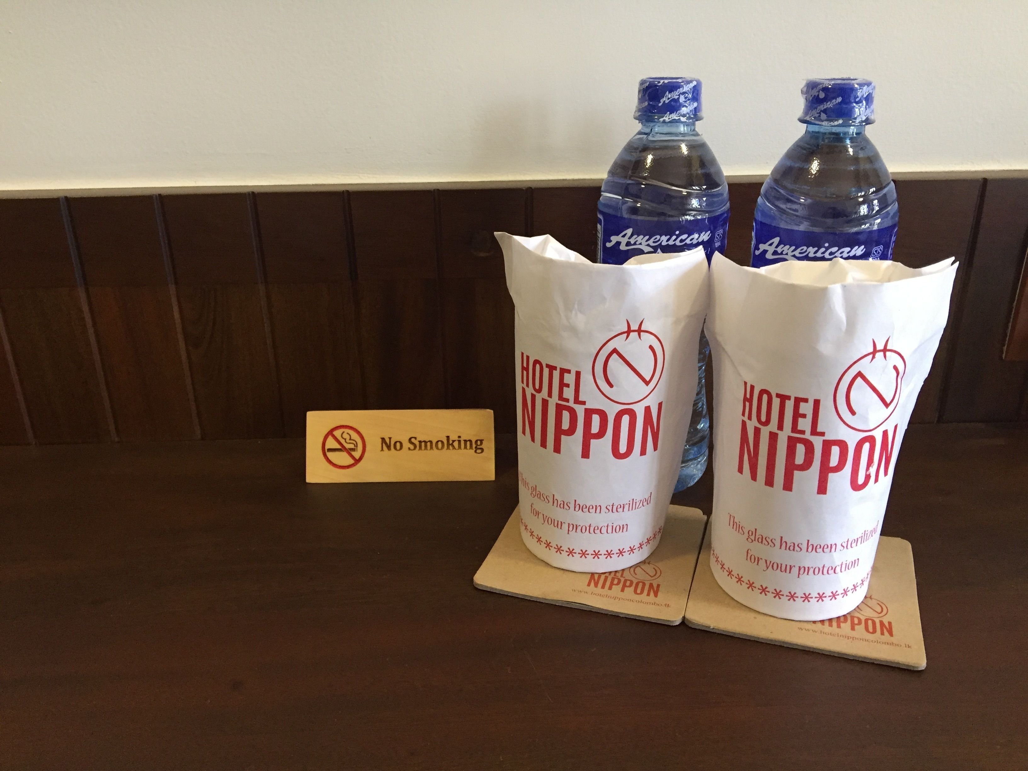 Dues bosses d'ampolles d'aigua, amb les etiquetes 'American' i 'Hotel Nippon', i un cartell que diu 'No Fumar' a prop.