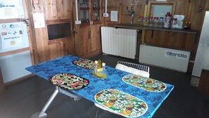 A dining area with a wooden interior, a table with a blue tablecloth, and a refrigerator labeled "Beretta". - 8000 Inn (Lobuche)