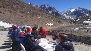 A group of people dining outdoors with a mountain backdrop. - 8000 Inn (Lobuche)