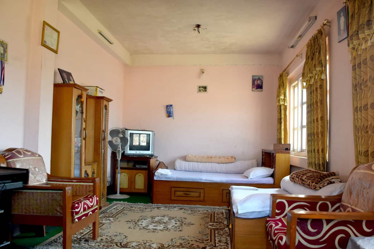 Una habitación con una cama, dos sillas, un televisor, un armario y una mesita.