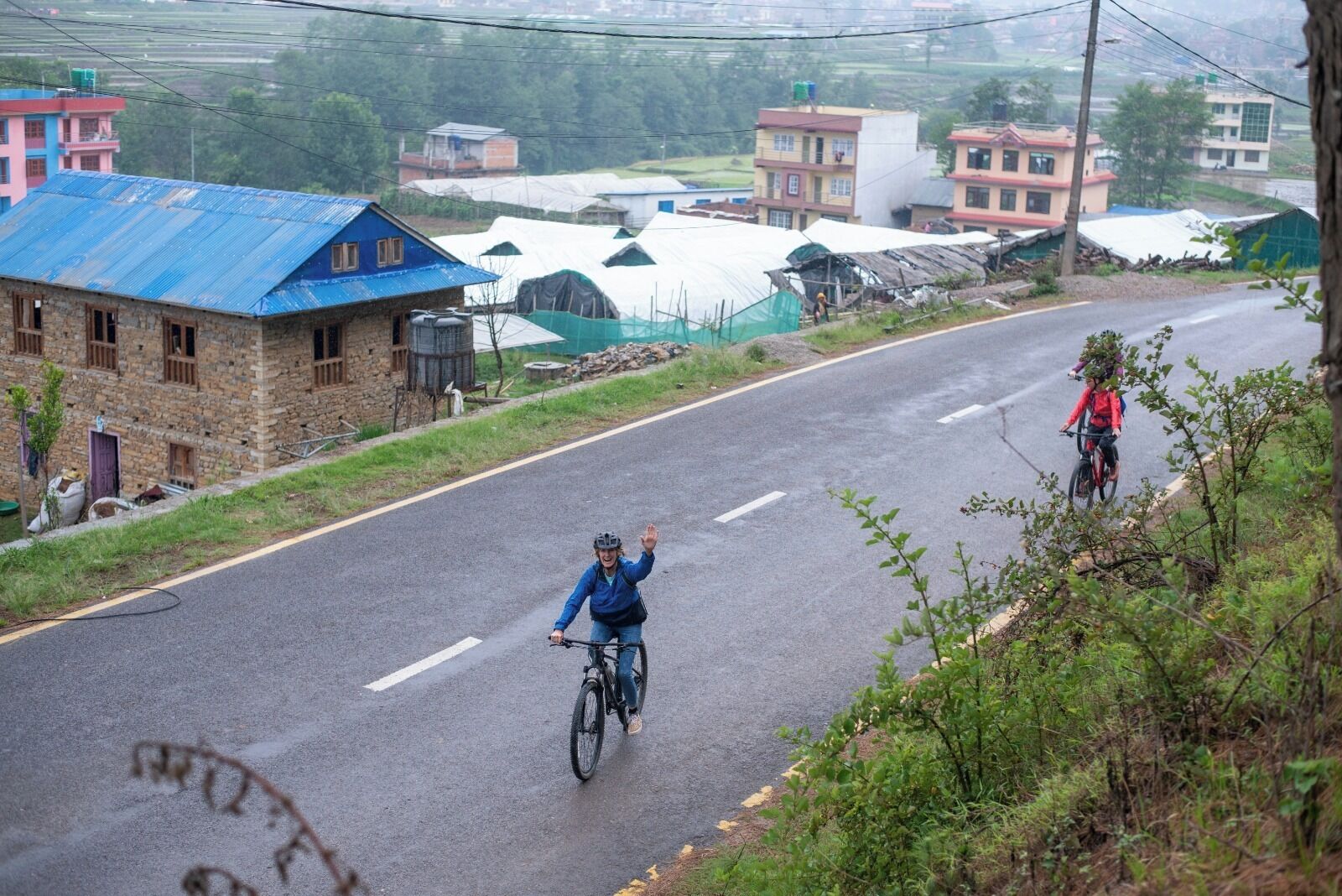 A rural road with houses and greenhouses.