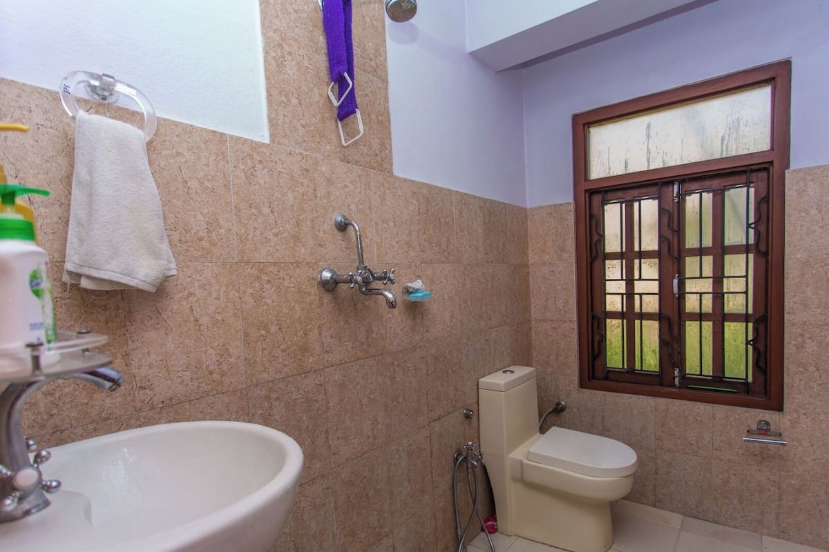 Un baño con lavamanos, inodoro, ducha y ventana.