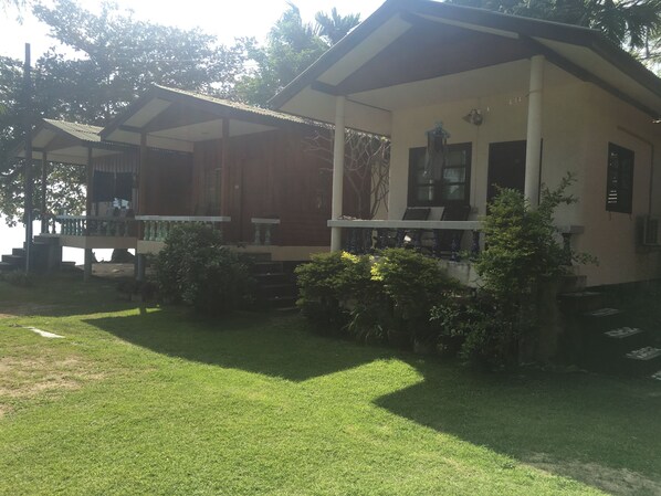 A two-story building with a covered porch and a small garden area.