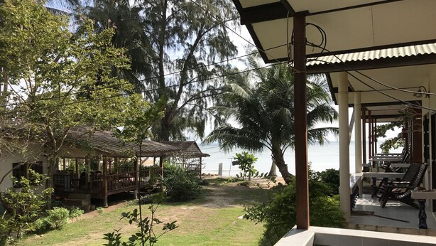 A covered outdoor area with a view of the sea, a small garden, and a wooden structure. - Blue Lotus Resort (Ko Pha-ngan)