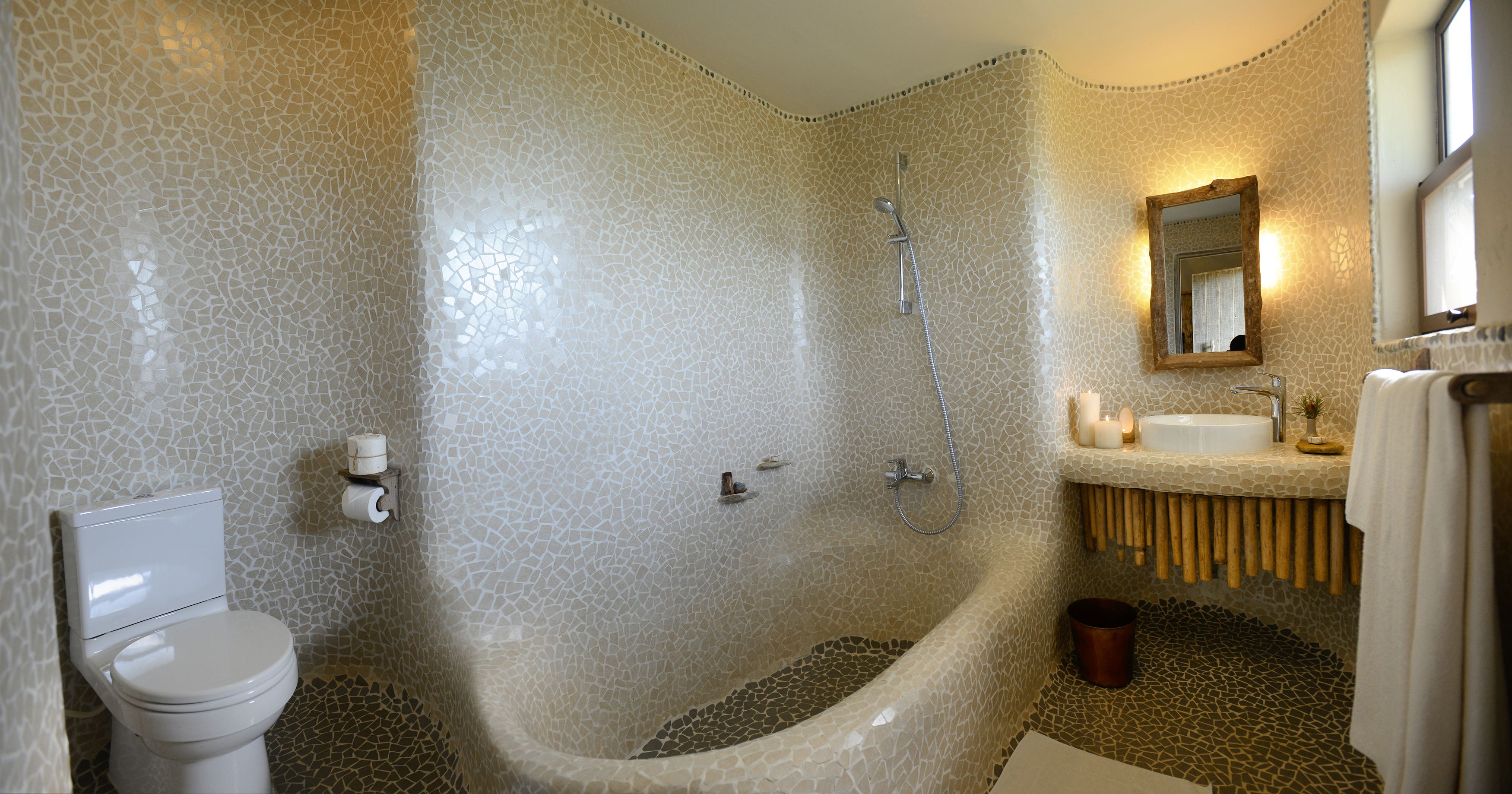 Un baño con pared de mosaicos, una bañera, un inodoro y un lavabo con espejo.
