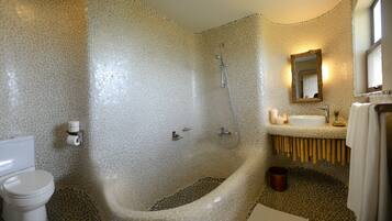 Un baño con pared de mosaicos, una bañera, un inodoro y un lavabo con espejo.