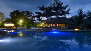 Relax by the serene pool surrounded by lush trees and comfortable lounge chairs.