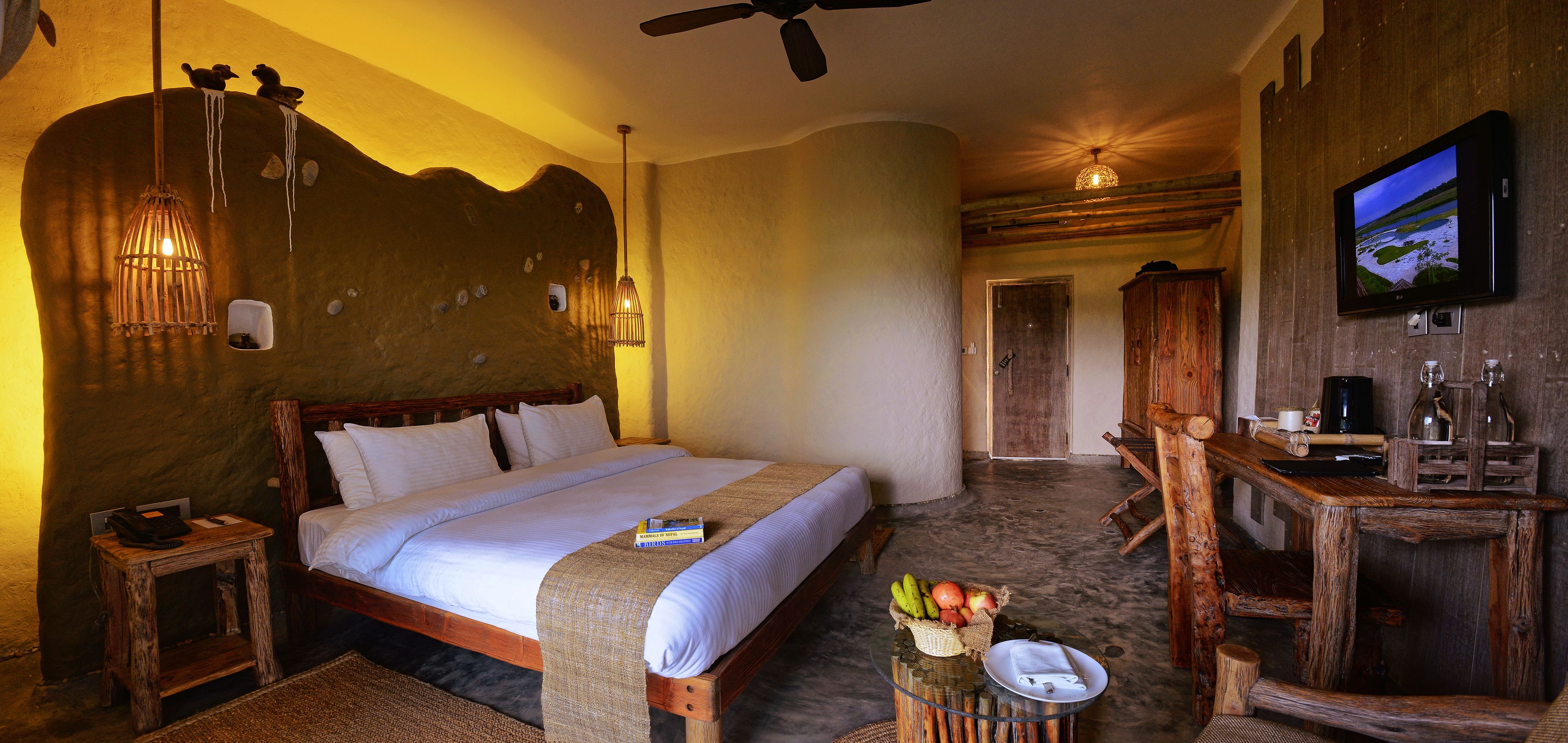A spacious bedroom with a large bed, wooden headboard, and a television mounted on the wall.