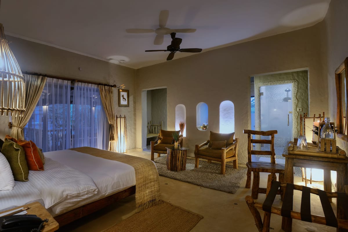 A spacious bedroom with a large bed, a ceiling fan, and a view of the outdoors through the windows.